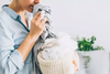 Woman smelling clothes from a knit laundry basket