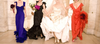 Bride in full wedding attire holding a pale pink bouquet on a stony beach