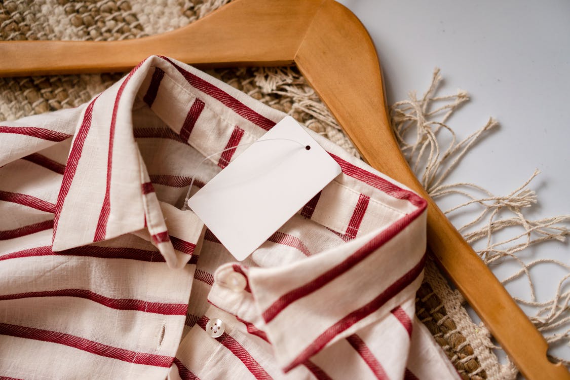 White and red striped shirt with a wooden hanger lying on a rug