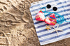 Bikini top and sunglasses lying on top of a striped blue and white towel