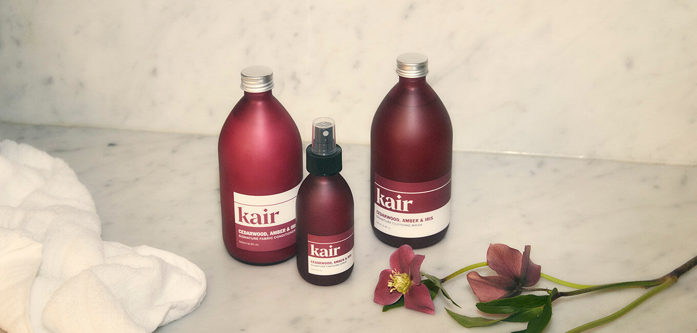 Kair Signature Bundle in Cedarwood, Amber & Iris scent next to a soft towel and a flower