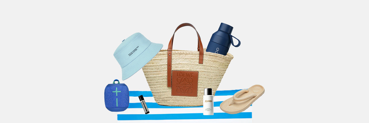 Wicker beach bag with sunglasses and sandals on a white sandy beach 