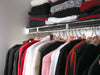 Clothes folded on a shelf and hanging on a rail in a range of colours (grey, red, white, pink)