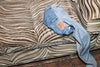 A pair of blue denim jeans lying on a zebra-stripe sofa