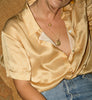 A woman wearing a yellow silk blouse and blue denim jeans