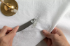 Photo of a knife being used to scrape wax off a white tablecloth