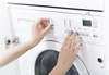 Woman turning dials on washing machine