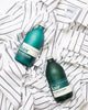 Wild Juniper & Bergamot Signature Clothing Wash & Signature Fabric Conditioner lying on top of a striped white WNU shirt