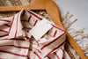 White and red striped shirt with a wooden hanger lying on a rug