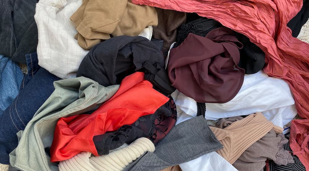 Clothes in a pile on the floor in lots of bright colours 