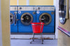 Three retro blue washing machines with a red laundry basket in front