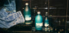 Kair Signature Bundle - Wild Juniper & Bergamot on a black tile background next to a pair of denim jeans